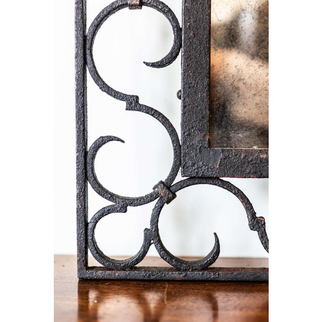 A French iron mirror from the 20th century with arching silhouette and S-scroll motifs. This 20th-century French iron...