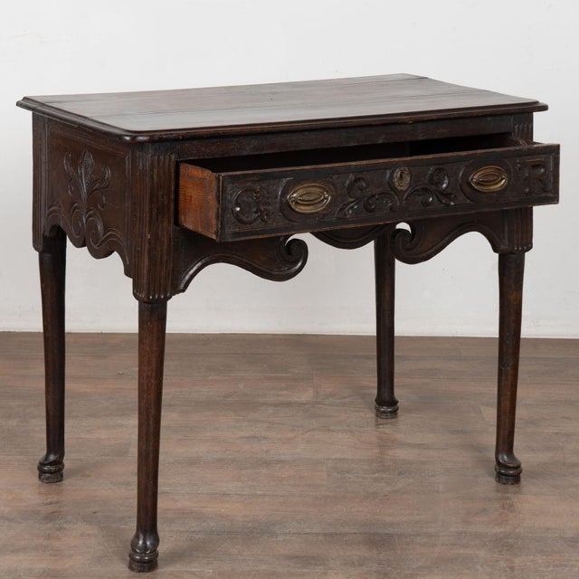 Carved walnut side table with single drawer. The drawer is accented with carved embellishments, and the table features a...
