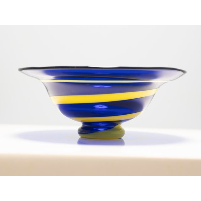 This decorative glass bowl dates to the 1960s and exemplifies mid-century art glass through its expressive use of color...