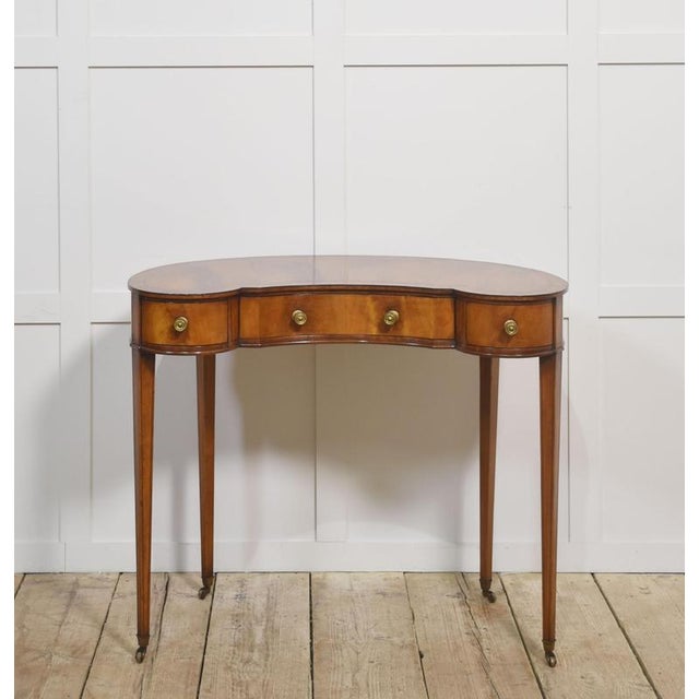 Mahogany lady’s dressing table, the kidney-shaped top, above three frieze drawers. Raised on square tappering supports...