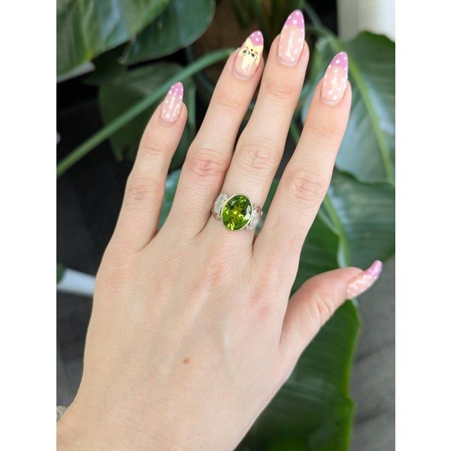 5.8 carat oval peridot set in solid 14K gold, radiating vibrant lime-green brilliance. Accented with natural diamonds,...