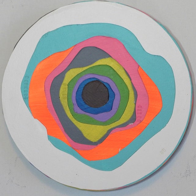 This artwork features a vibrant circular composition that layers concentric shapes in bold colors, creating a dynamic...