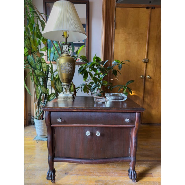 This compact antique cabinet reflects the late American Empire Revival style, with a bowed front and rich dark-stained...