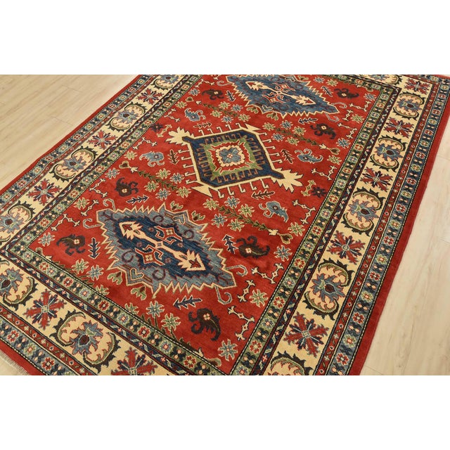 A tribal Kazak rug hand-knotted with fine wool with silk highlights on a cotton foundation. This oriental rug features...