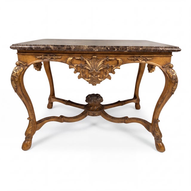This is a 20th century French Louis XV style heavily carved fruitwood and gilt marble top table by Maitland -Smith. The...