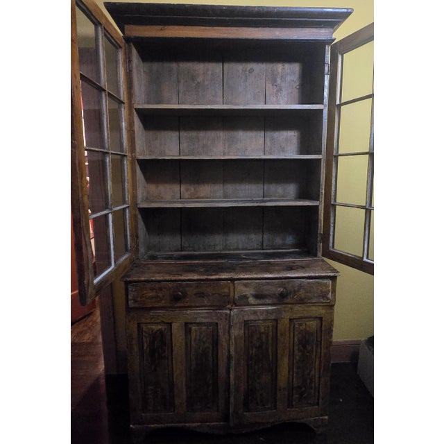 Early 19th century glazed cupboard constructed as a single-piece form in pine with a heavily worn, original painted...