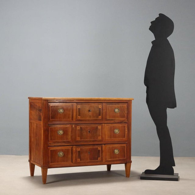 Neoclassical walnut chest of drawers. The front features three tripartite drawers with maple and mahogany trim, fir...