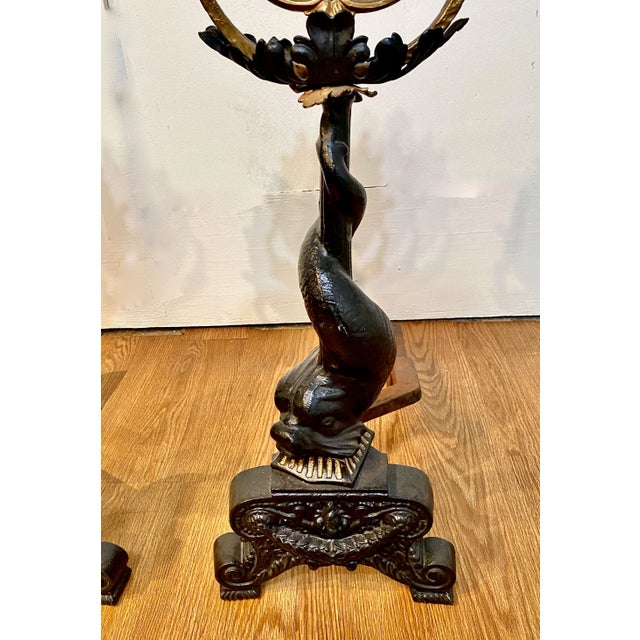 This is an exceptional pair of large c. 1850 cast iron andirons. The andiron shaft is composed of a mythological dolphin...