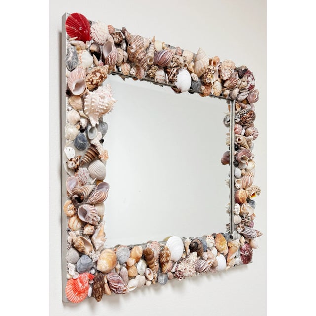 Beautiful vintage hand-crafted wall mirror encased in varied sea shells. Wood frame painted in a metallic silver. Beveled...