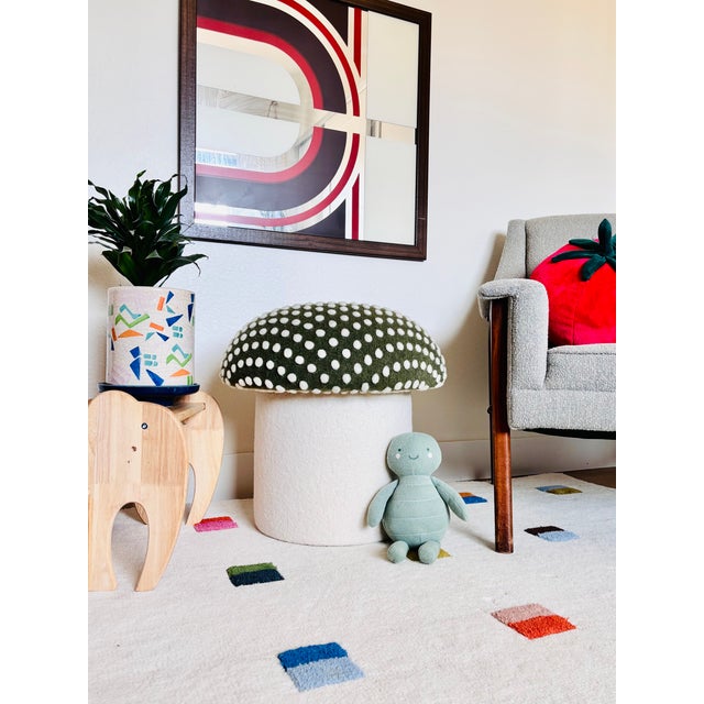 A handmade mushroom shaped ottoman, upholstered in a dotted wool blend fabric to resemble a green fly agaric mushroom....