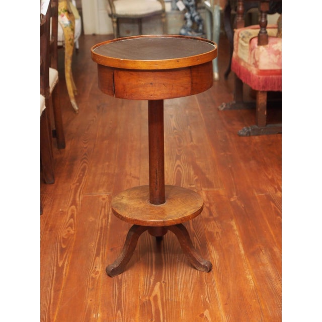 A charming 19th century table, the top, with a drawer, in the form of a drum and covered in black leather-like canvas. The...