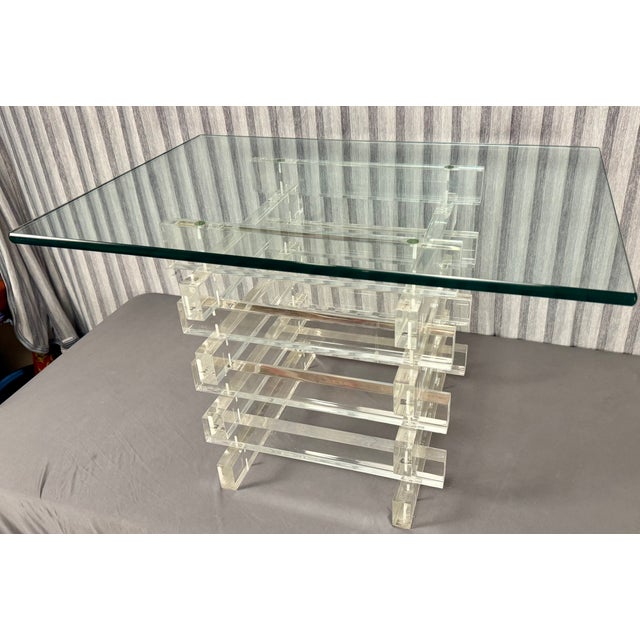 This is a 1970s vintage-style stacked lucite coffee table featuring a glass top and a base made of interlocking clear...