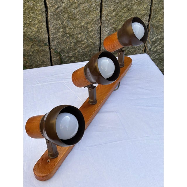 Vintage ceiling light with three adjustable spotlight shades made of brown lacquered metal on an elongated wooden strip,...