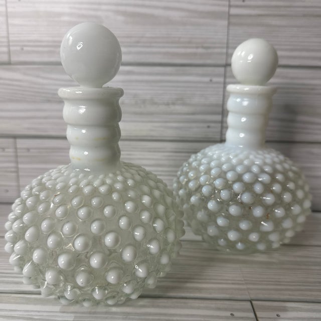 This stunning set of vintage Fenton hobnail bottles showcases the timeless elegance of white milk glass. With their...