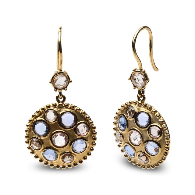 Colorful blue sapphires with brown and white diamonds combine to create a striking motif in these cluster medallion...