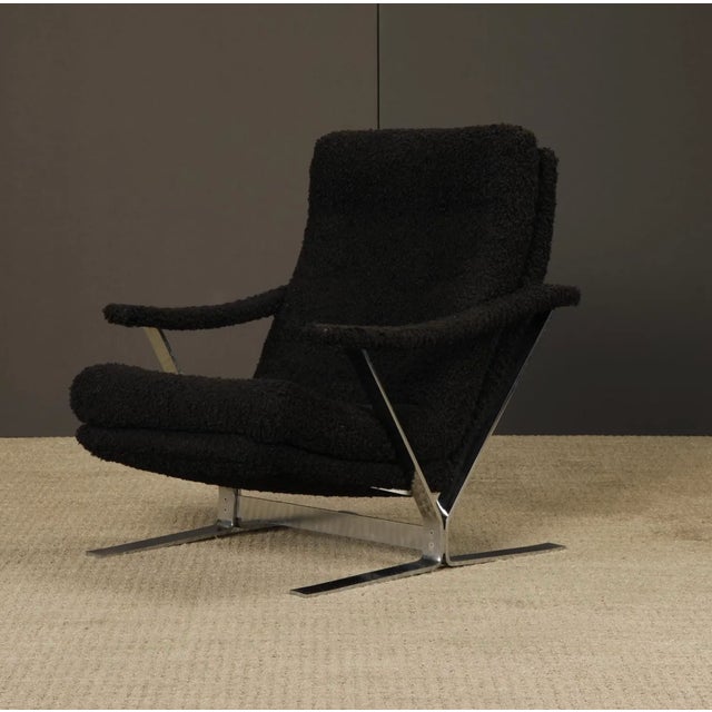 Striking mid-century modern lounge chair featuring a sculptural chrome X-base frame and deep cushioned seat with textured...