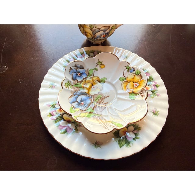 Made in Longton, Staffordshire, England, this stunning two-piece set showcases a vibrant, romantic pansy motif featuring...