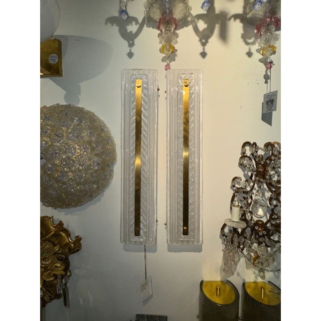 The "Textured Murano Glass and Brass Sconces featuring a unique combination of materials. The sconces are crafted from...