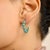 These elegant hoop earrings are crafted in 18K yellow gold, showcasing round cabochon-cut turquoise gemstones with a total...