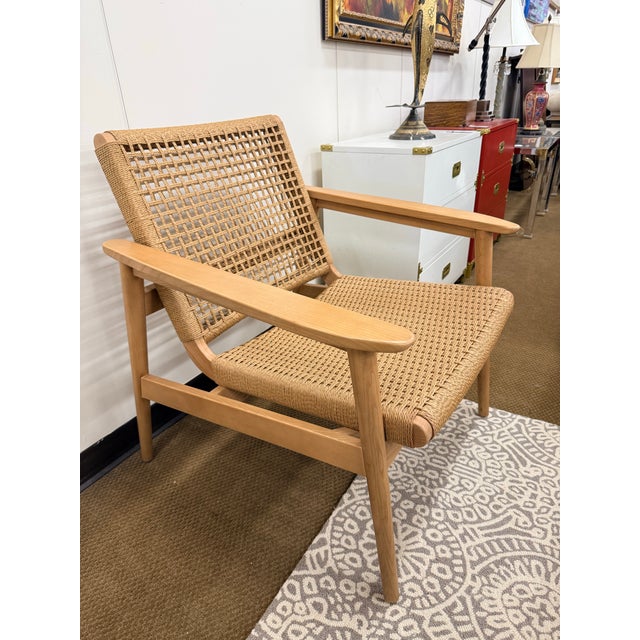 A beautifully crafted lounge chair that blends sculptural mid-century lines with the warmth of handwoven natural fiber....