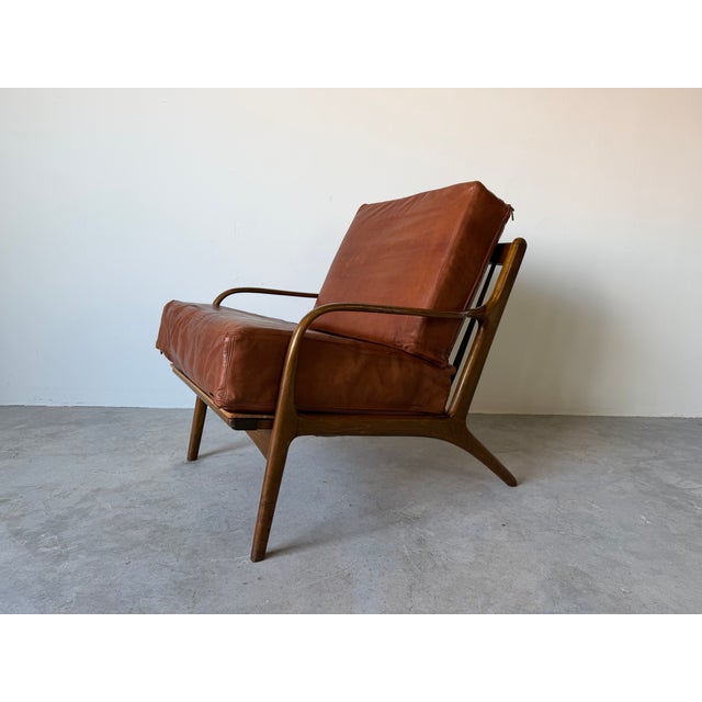 Vintage 1950s Mid Century Modern Danish lounge chair crafted with a beautifully sculpted solid wood frame and elegant...