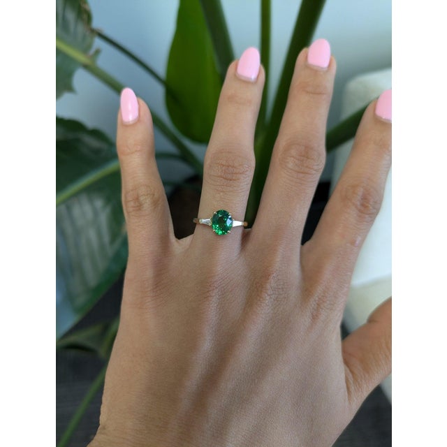 A 1.87-carat tsavorite garnet blazes in vivid, grass-green at the center of this solid 18K yellow gold ring, flanked by...