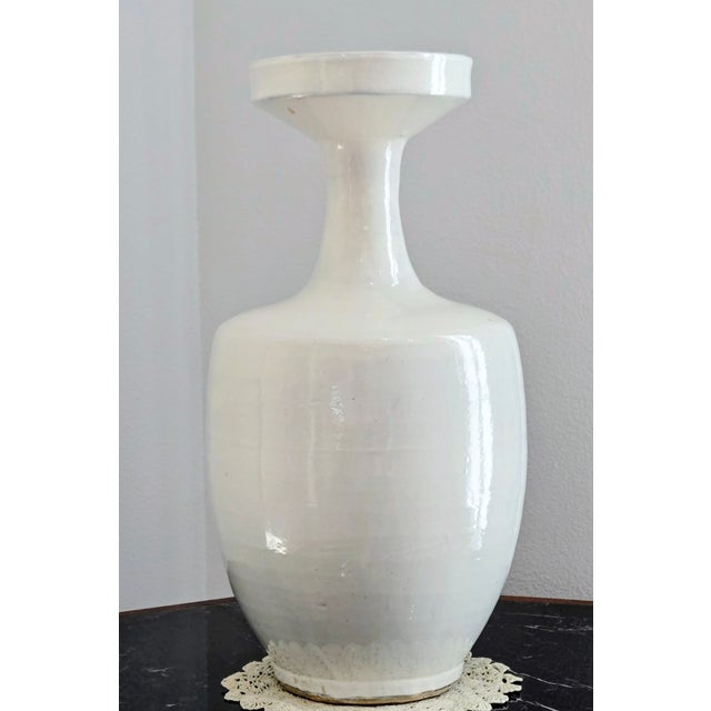A striking tall white studio pottery vase featuring a sculptural flared collar and clean modern silhouette, perfect for...