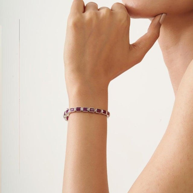 Bold, geometric, and richly elegant, this Art Deco inspired ruby tennis bracelet makes a striking statement on the wrist....