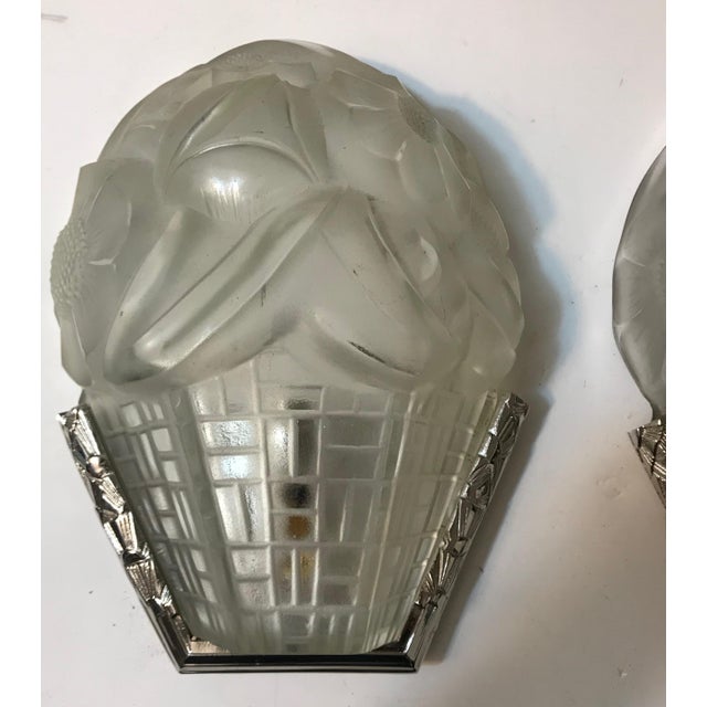 Pair of French Art Deco wall sconces signed by the French artist “Degue” in clear frosted glass shades with floral motif....