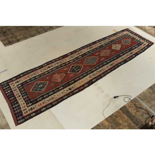 Handwoven in wool, a 4x12 kilim rug from our vintage selections. Originating from Turkey circa 1950-1960, the mid-century...
