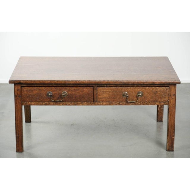We are offering this charming antique English oak coffee table from the 20th century, featuring two drawers. Thanks in...