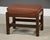 An arts and crafts oak footstool by L. & J.G. Stickley with a leather cushion ready to be place in front of a lounge...