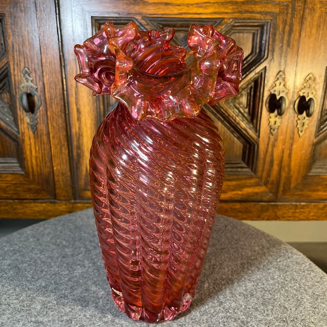 Vintage cranberry colored glass vase with ruffled edge and a tight swirled pattern. Nice size, form, and weight to this...