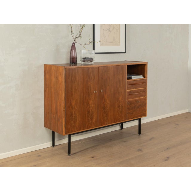 A wonderful highboard from the 1960s. High-quality walnut veneer cabinet with two cabinet doors, a drop-down compartment,...