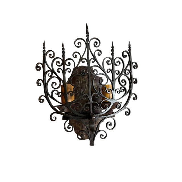 A rare pair of intricate wrought iron with hammered iron backplates wall sconces. Perfect for either side of a fireplace...