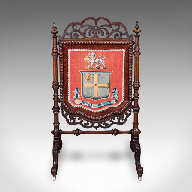 This is an antique armorial embroidered panel screen. An Irish, walnut and needlepoint house insignia firescreen, dating...