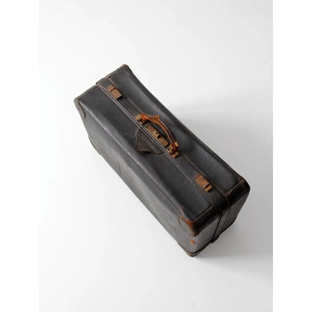 Beautifully aged vintage black leather suitcase from the early 20th century, featuring a structured hardboard frame...