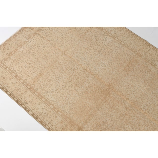 This is a vintage Turkish Oushak rug from the Mid 20th Century. The piece was hand-knotted.