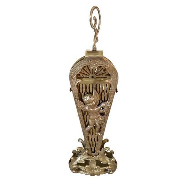 Large brass peacock fan fireplace screen with a decorative cherub at the base and overlapping brass blades that open into...