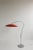 Arched floor lamp with bright orange-red saucer-shaped shade. A unique and modern touch.