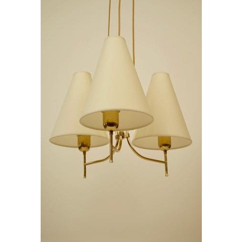 An elegant pendant lamp from the 1950's in brass with three shades. This is a beautifully composed lamp made up of just a...