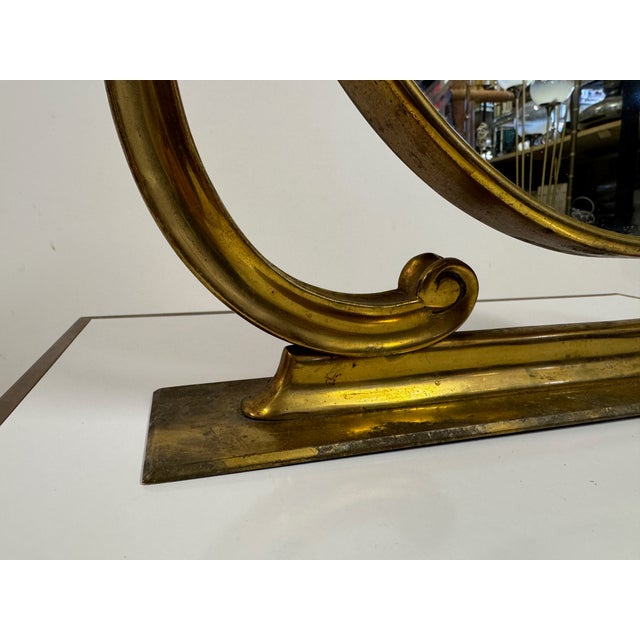 A mid-century Italian vanity mirror in brass, dating to the 1950s, with an elegant, neoclassical-inspired silhouette. The...