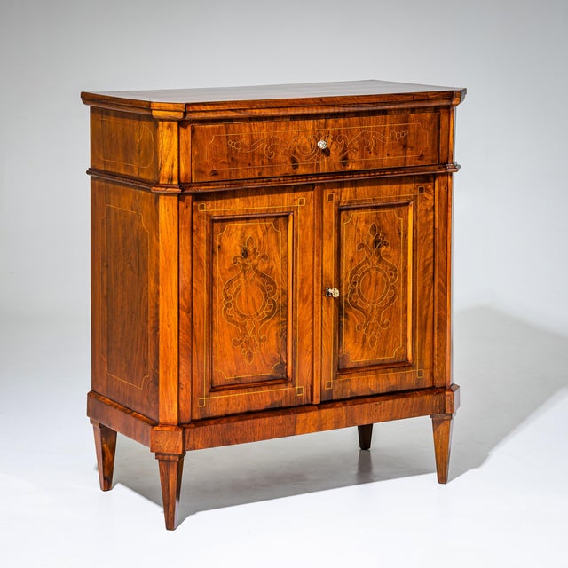 Half cabinet with two doors and one drawer, standing on tapered square legs. The case features slightly projecting,...