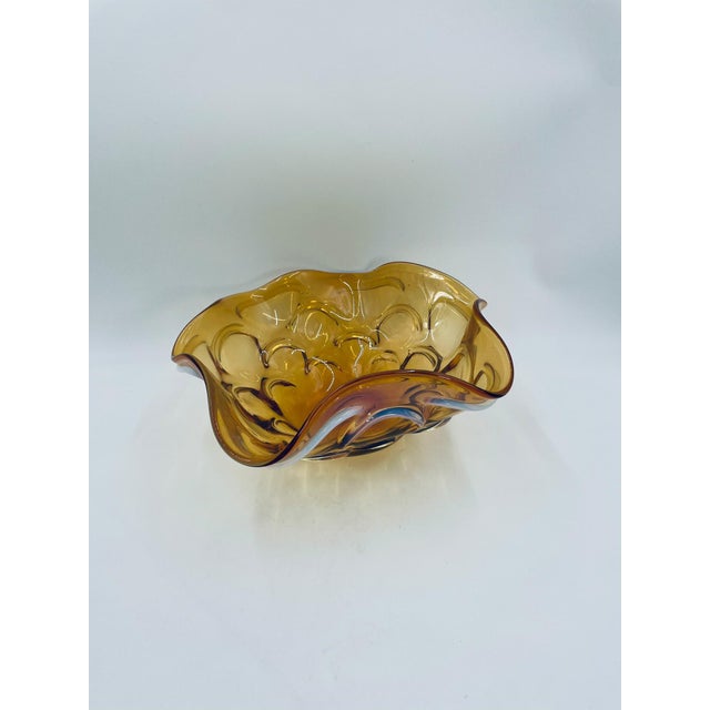 A decorative vintage-style bowl from the 1960s/70s, crafted from high-quality art glass. The bowl features a warm, honey-...