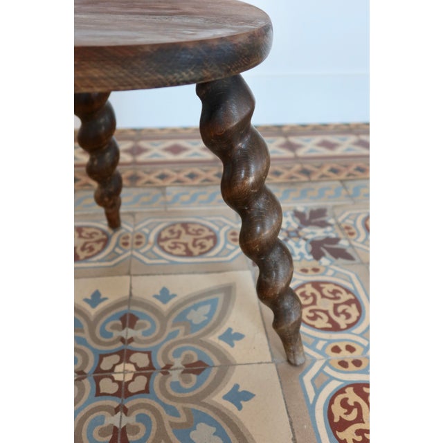 Solid wood tripod stool, characterized by its three twisted legs that give it an elegant and distinctive silhouette. The...