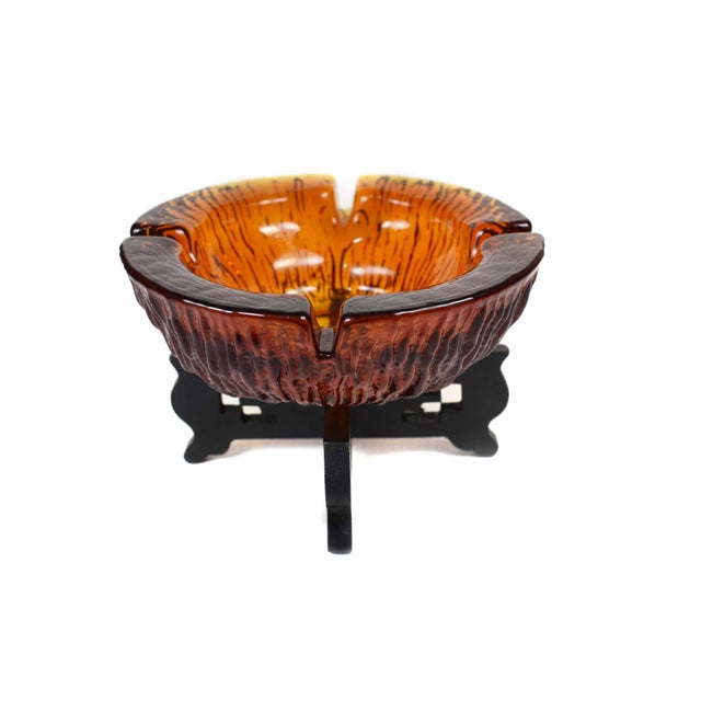 This stunning mid-century modern ashtray is crafted from thick, amber-colored glass with a unique textured surface that...
