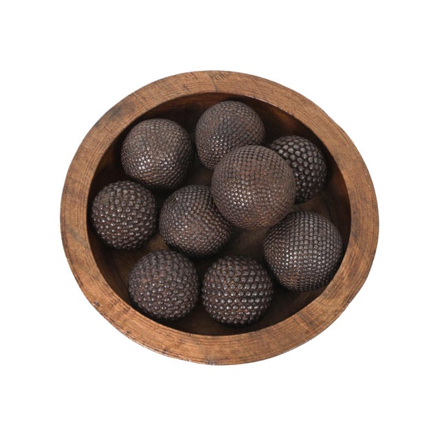 A hand-carved wooden bowl with nine antique nail-studded iron boules that were used for boule Lyonnaise or pétanque games....