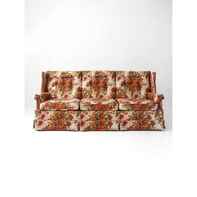 This vintage 1960s–1970s sofa features richly patterned pheasant and floral upholstery in warm rust, red, green, and...
