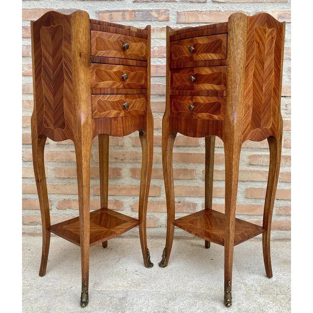 Pair of French walnut bedside tables adorned with fine Louis XV marquetry from the early 19th century. This pair of French...
