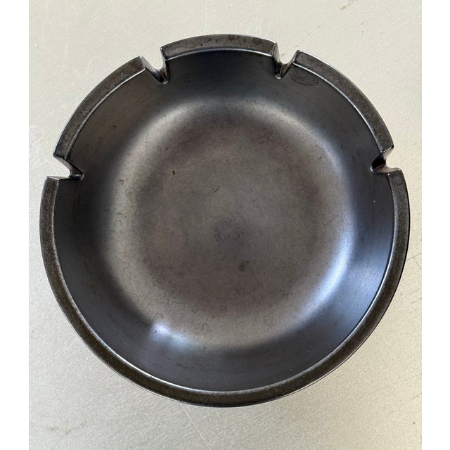 A classic Heath Ceramics ashtray in a rich matte gunmetal/charcoal glaze with four cigarette rests. Clean, architectural...